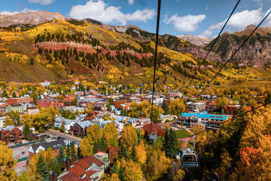 a gondola descending into a town filled with fall foliage