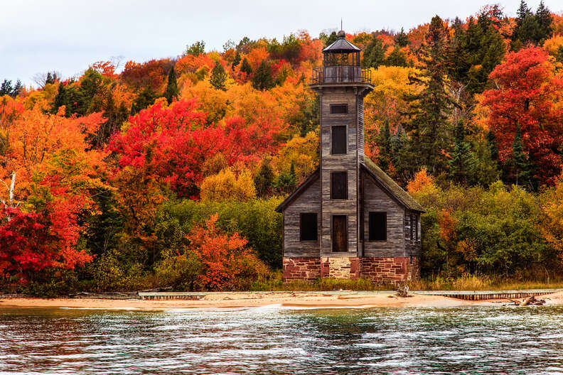 a wooden lighthouse on a lakefront in fall