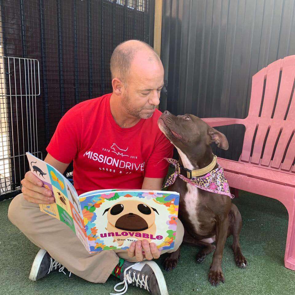 Man reading book to shelter dog