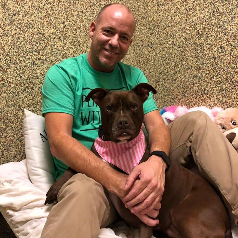 Man cuddling with dog in her kennel