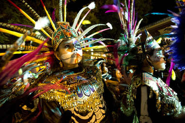 people in elaborate Dia de Los Muertos costumes in a parade