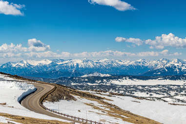 road in the mountains with larger snowy mountains in the distance