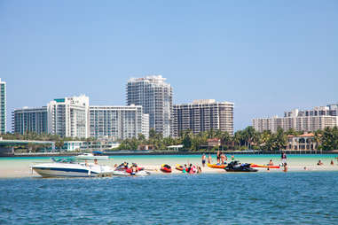 City skyline behind people and speedboats on beach