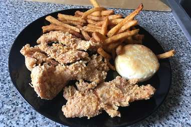 Popeyes chicken tenders, Cajun fries, and biscuit on a plate