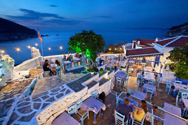 people dining outside near the water in skopelos, greece