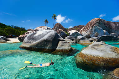 a woman snorkeling in clear water between the rocks of Virgin Gorda, British Virgin Islands, Caribbean