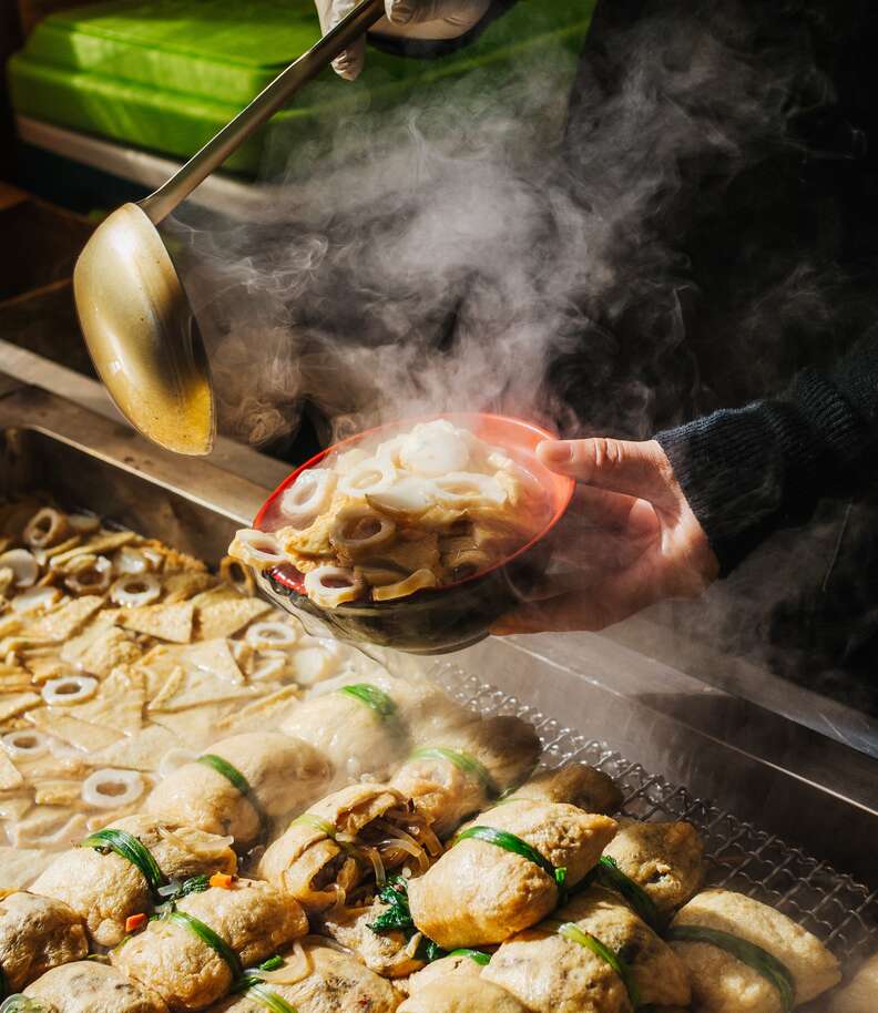 a person holding out a bowl of steamy fish cakes in Busan, Korea