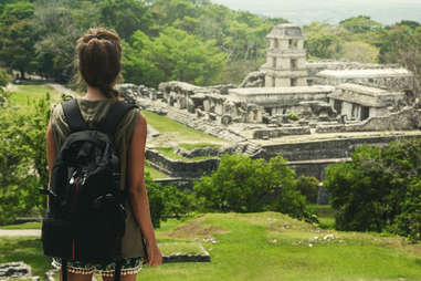 a woman backpacker overlooking the Ancient Mayan ruins of Palenque in Chiapas, Mexico