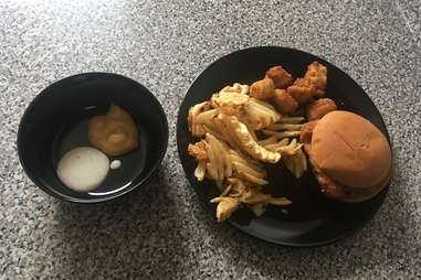 Ranch sauce and Chick-fil-A sauce in a bowl. Waffle fries, chicken nuggets, and chicken sandwich on a plate. 