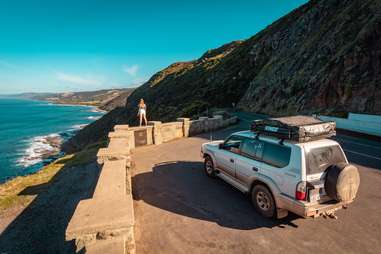 woman and a car standing on a seaside road on the Great Ocean Road, Anglesea Victoria, Australien