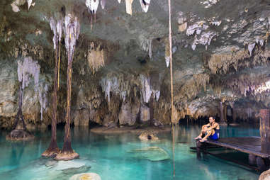 a man sitting on the edge of a cave pool