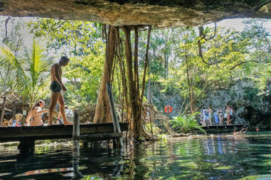 person standing on a dock in a cenote