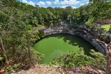 an enormous natural pool in the ground surrounded by forests