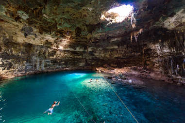 people swimming in an enormous underground natural pool