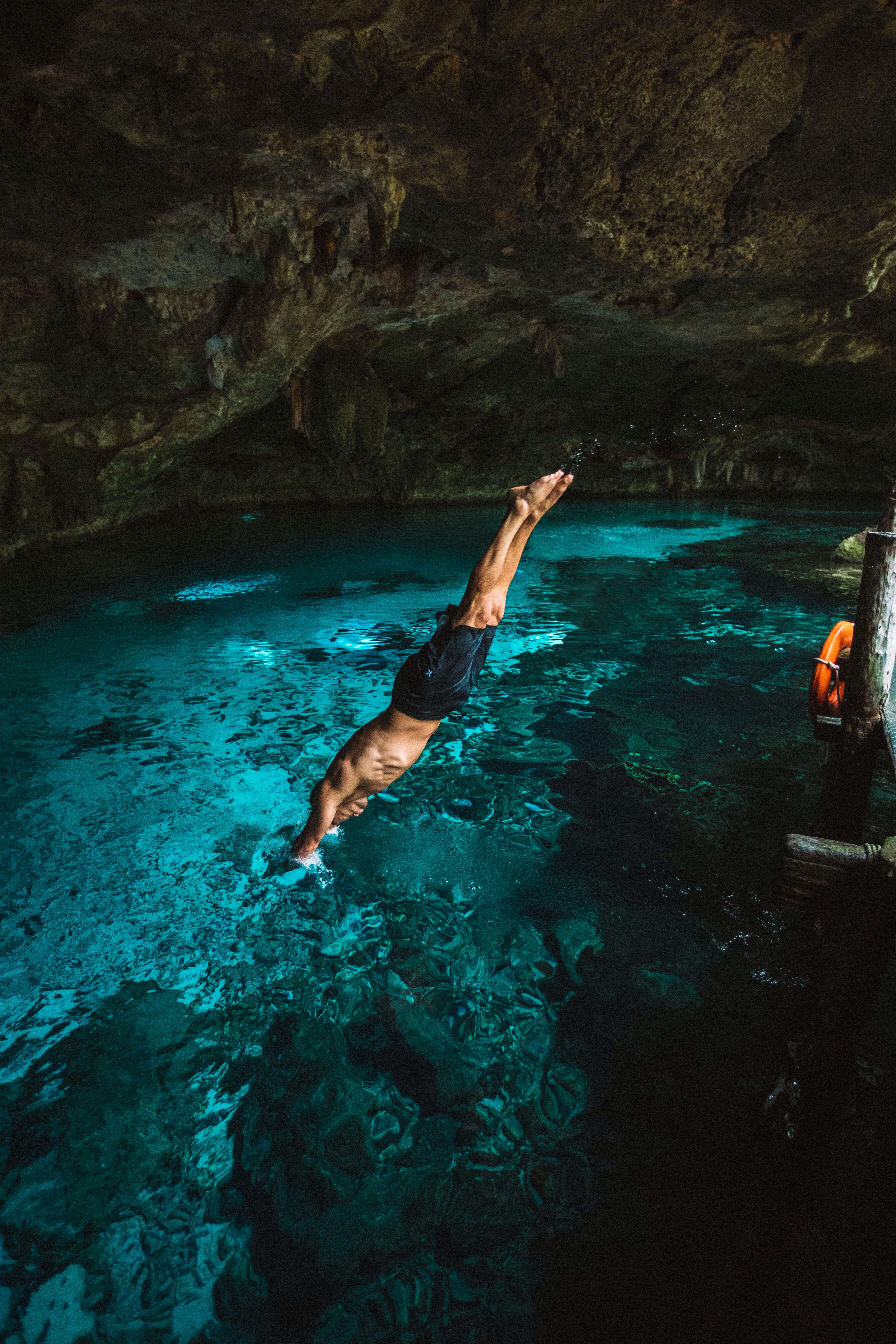 person diving into an underwater cave