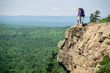 man and his dog standing at the edge of a cliff