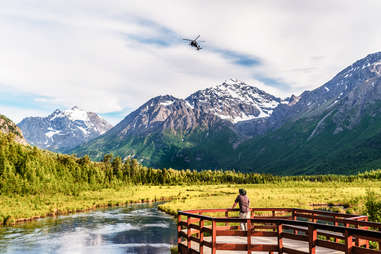 a person gazing out over a river toward a snowy mountain range