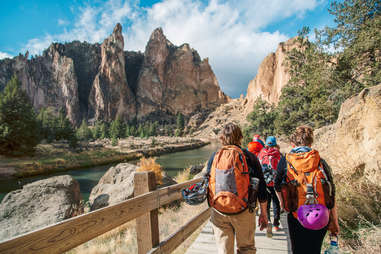 a group of backpackers hiking on a boardwalk near a rock canyon