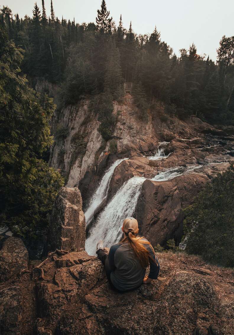 woman sitting in front of a waterfall