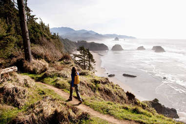 person walking along a trail above a beach