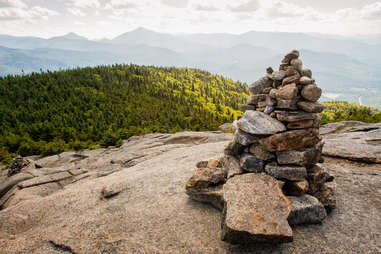 a stack of rocks overlooking a forest and mountains
