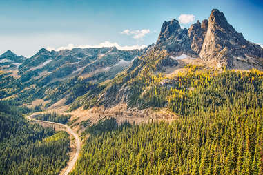 a road through forests leading to a mountain