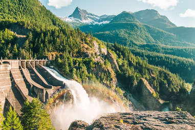 a dam surrounded by a mountains of pine trees