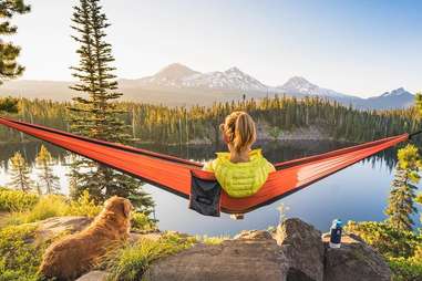 a person in a hammock in front of a mountain lake
