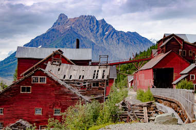 a rickety red mining town in front of a mountain
