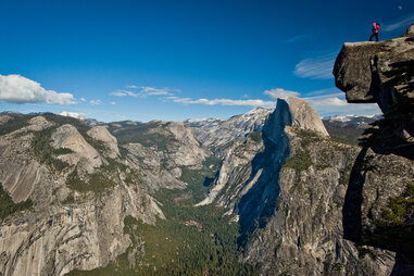 a person standing on a cliff above an enormous valley