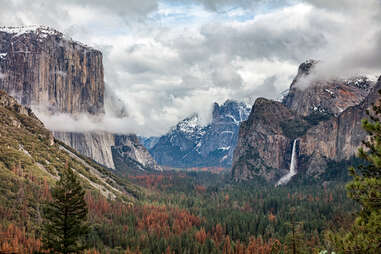 a view out across a forested valley toward various mountains and waterfalls