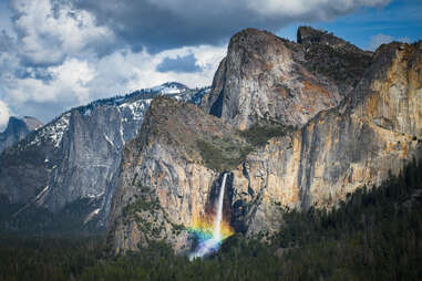 a waterfall falling into a valley lit by a rainbow