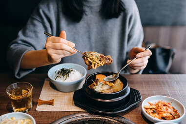person scooping meat and noodles from soup