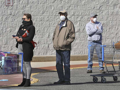 people wearing masks while they're waiting to get inside a store