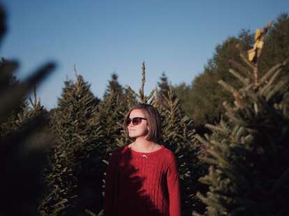 A person standing amid a Christmas tree forest.