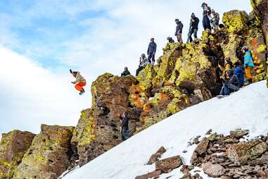 snowboarders doing jumps near enormous boulders