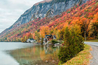 a small roadside cabin near a lake and enormous mountain in fall