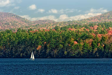 a sailboat on a lake against fall foliage