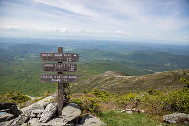a three-direction sign on a mountain peak with scenic views