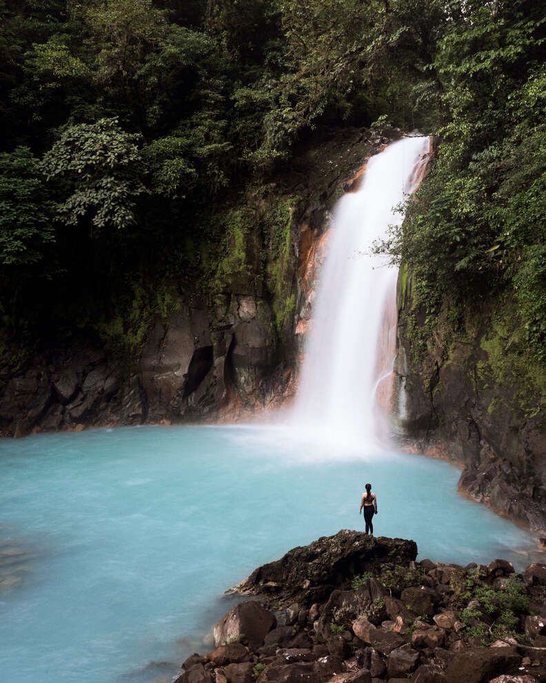 a person watching a waterfall in a jungle
