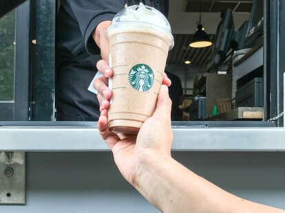 A drink hand-off through a Starbucks drive-thru window.