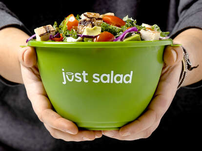 A person holds a Just Salad reusable bowl.