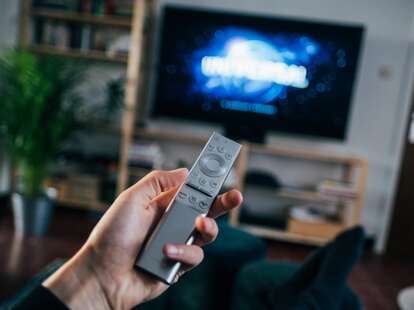 A person points a remote at a television. 