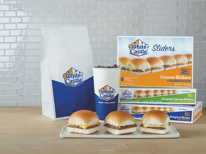 A White Castle takeaway bag, soda cup, and sliders on a plate.