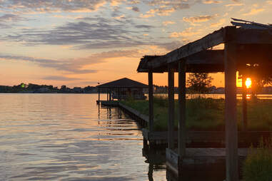 12 May 2019 Texas lake Conroe colorful sunset on lake with empty boathouse and green grass