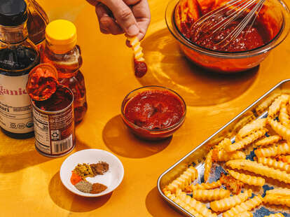 Hand dipping fry in ketchup