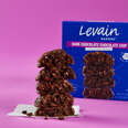 A box and a stack of Levain Bakery's dark chocolate chocolate chip cookies.