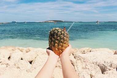 person holding pineapple on the beach