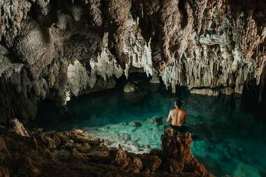 a person standing alone in an underground natural pool
