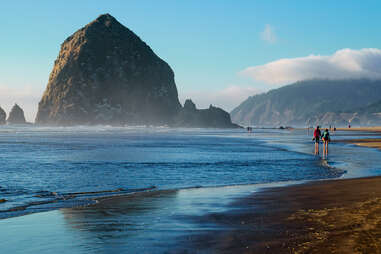 people walking along a beach marked by giant boulders